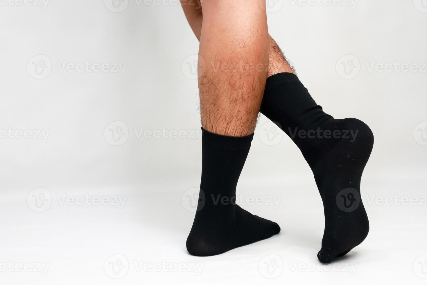 An isolated shot of hairy male legs and feet wearing plain black cotton socks photo