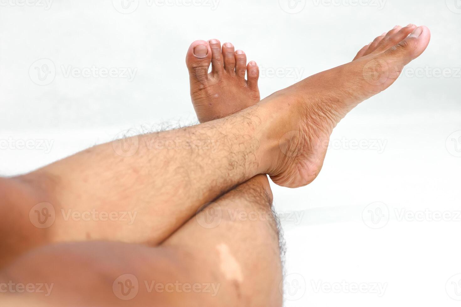 Relaxing with crossed legs and feet up, showcasing healthy skin and well-groomed toes against a white background photo