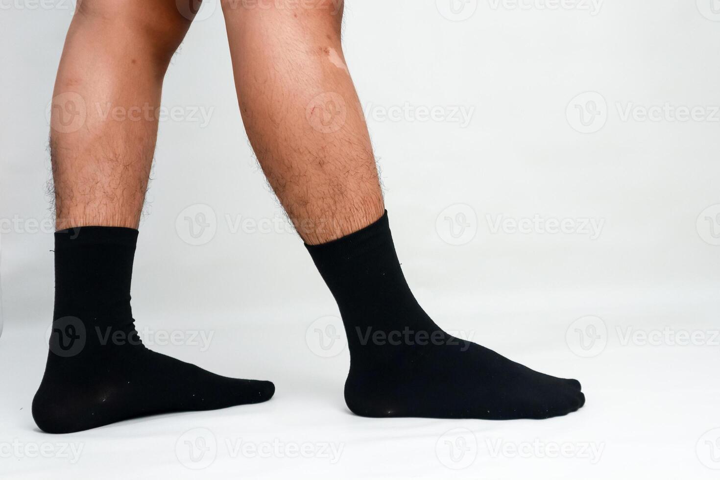 A man's legs wearing black socks in a standing position against a white background photo