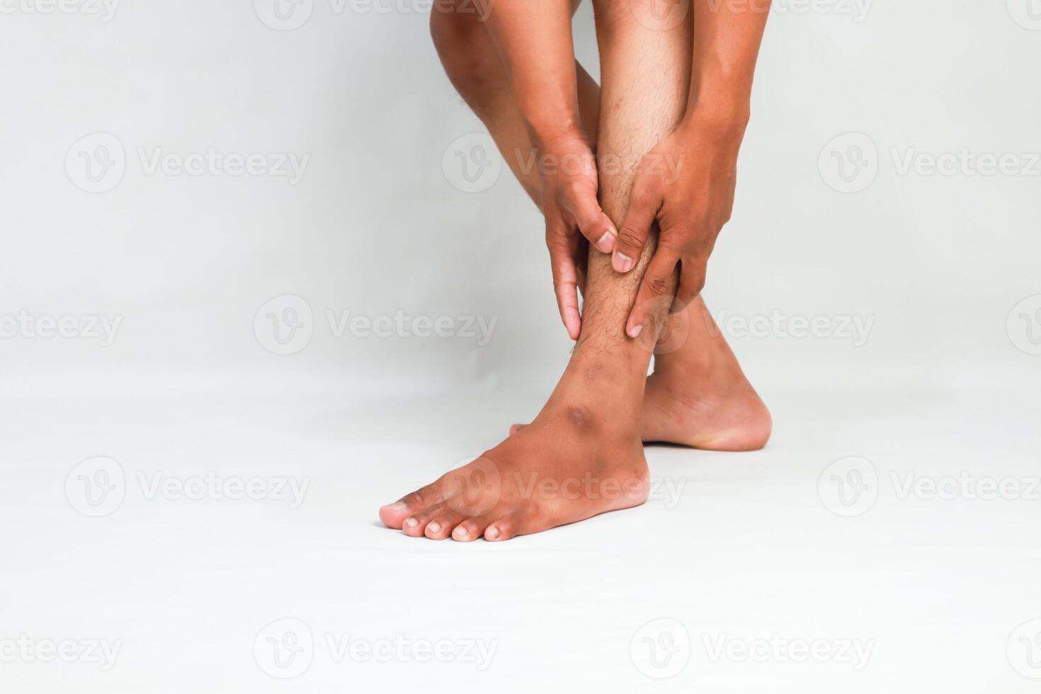 Person Holding Lower Leg with Pain on White Background Displaying Injury photo