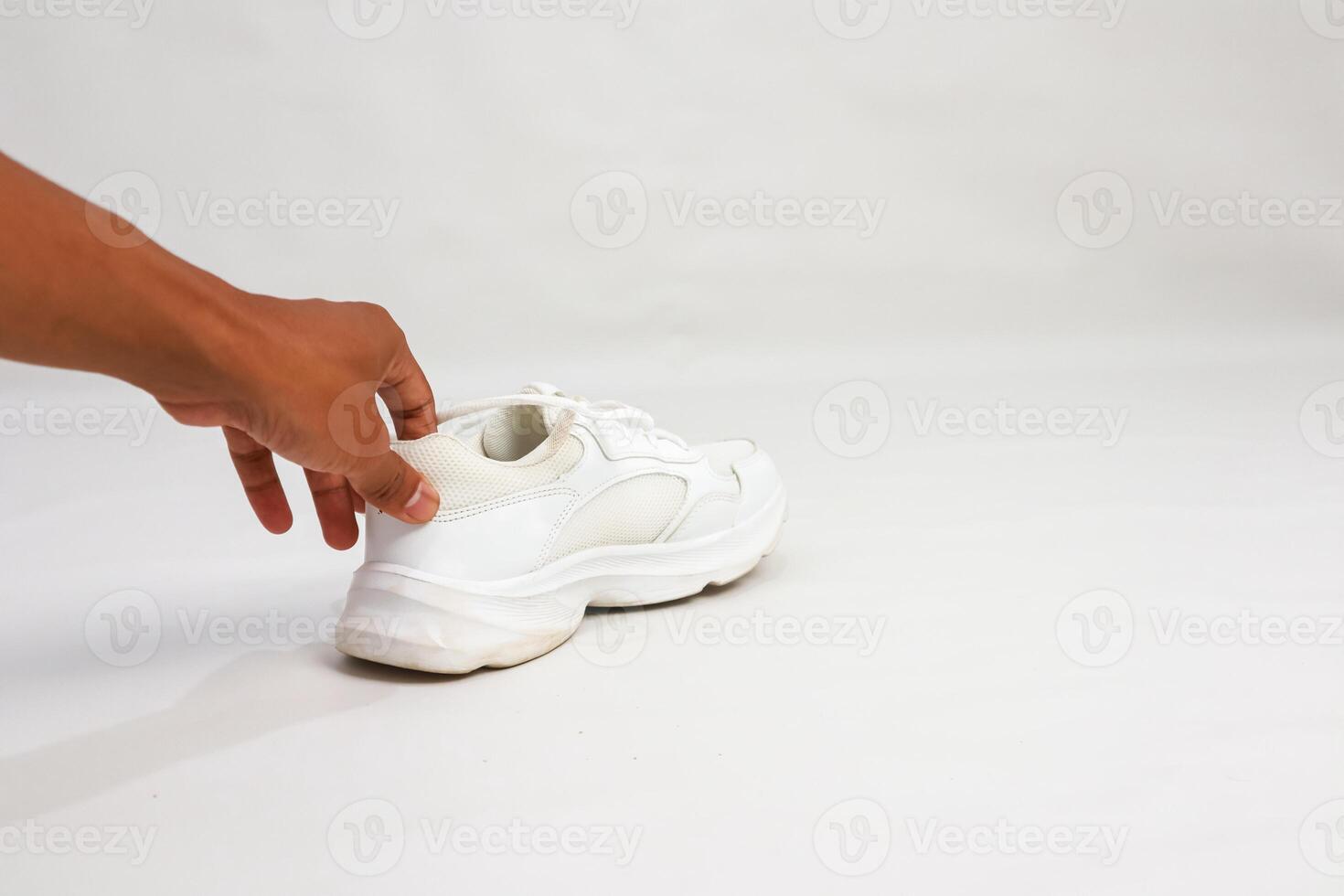 Hand holding a white platform sneaker on a white background, studio shot showcasing footwear and style photo