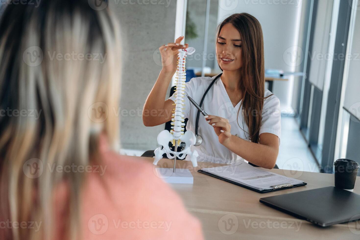 Spine problems, showing issue on model. Woman is on the consultation with doctor in clinic photo