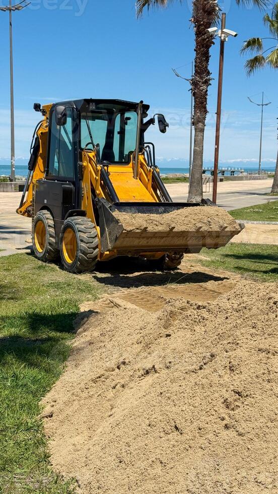 Skid Steer Loader Moving Sand in Coastal Landscape photo