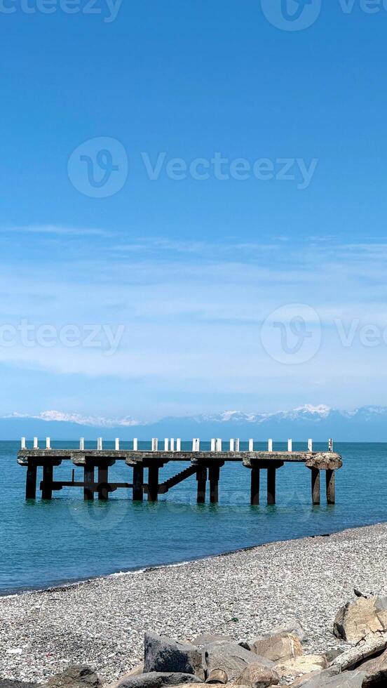 Aged Concrete Pier with Broken Columns Extending into Calm Sea photo