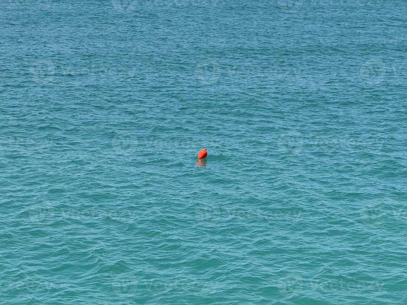 Solitary Orange Buoy Floating on Calm Open Water photo