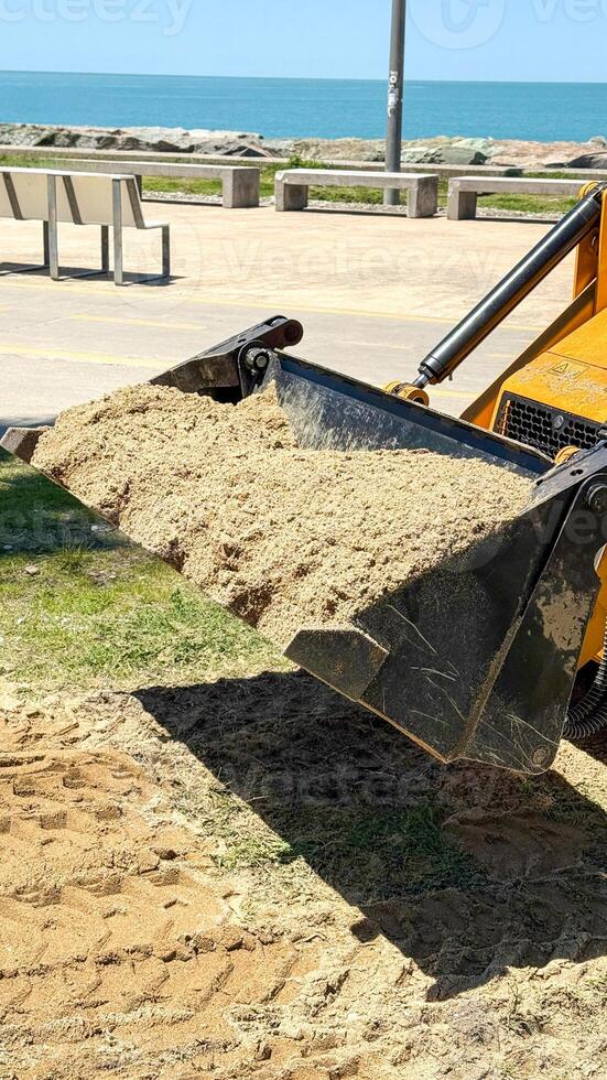 Front Loader Dumping Sand in Coastal Public Area photo