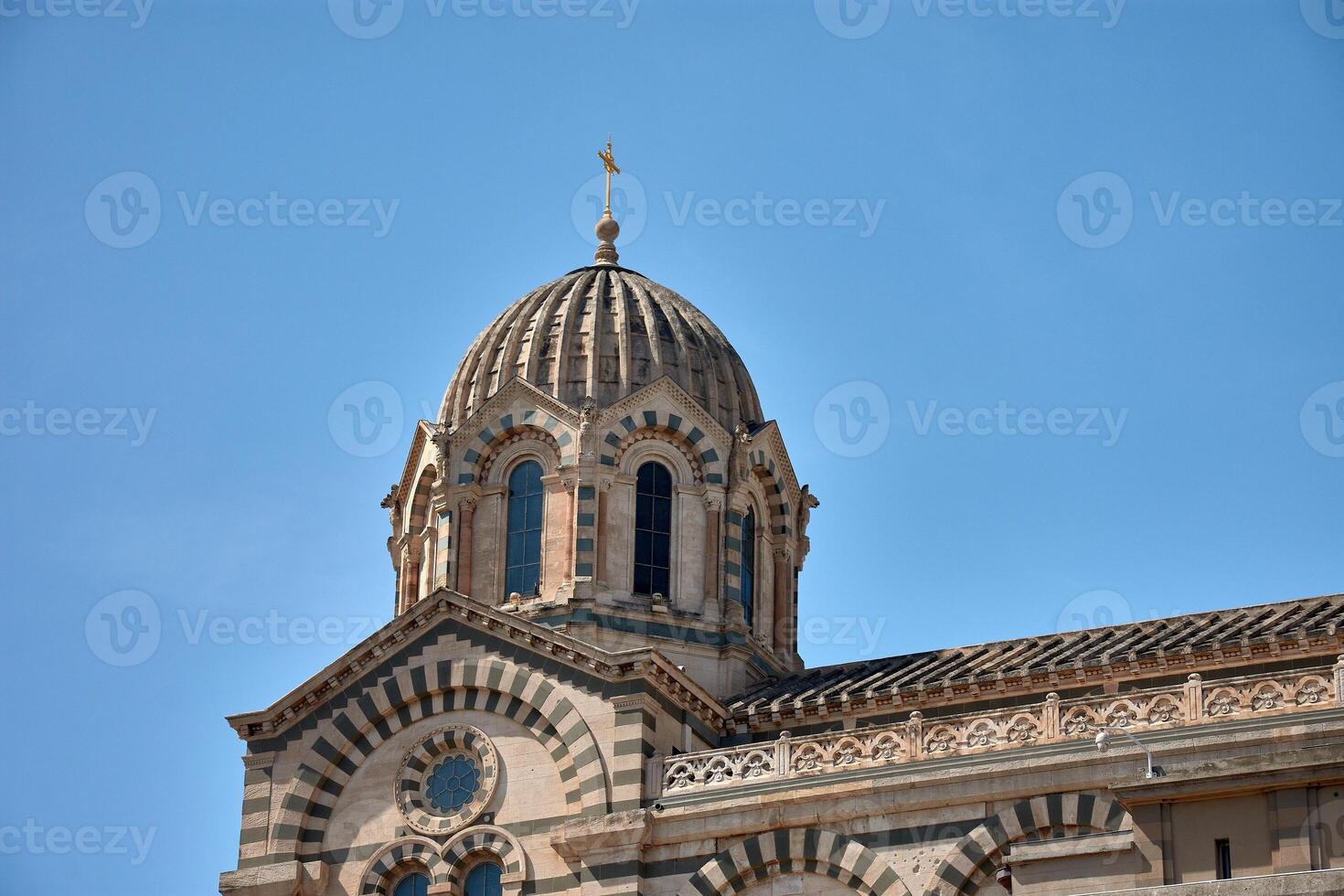 Dome and architectural details of Notre Dame de la Garde in Marseille, France, under a clear blue sky and intense natural light photo