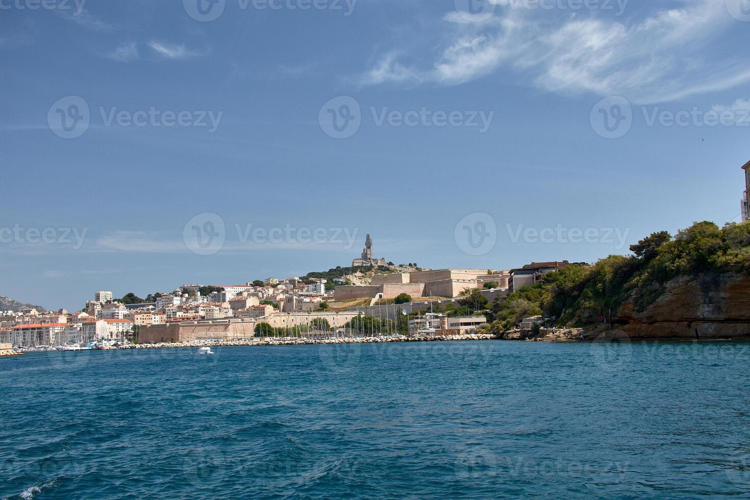 Boats docked in the Old Port of Marseille under a blue sky, captured from the sea on a calm Mediterranean day. photo