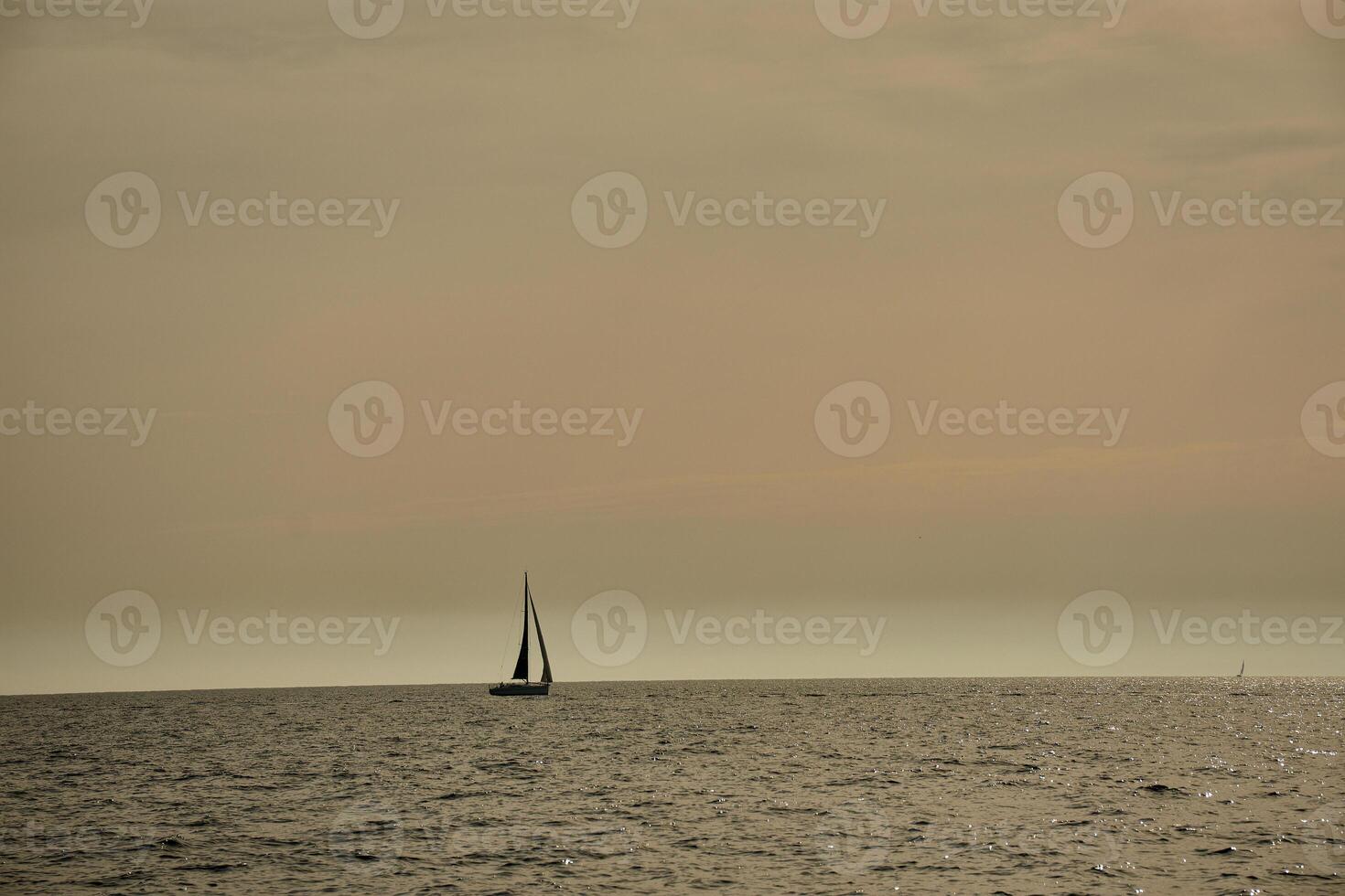 Sailboat sailing the Mediterranean Sea off Marseille, France, with a regatta and the rocky coast of Provence in the background photo