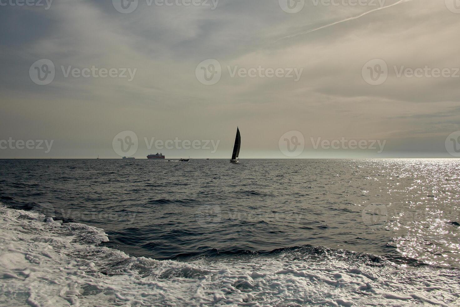 A sailboat sailing on the French Riviera off Marseille, Provence, surrounded by boats and hills under a clear sky photo