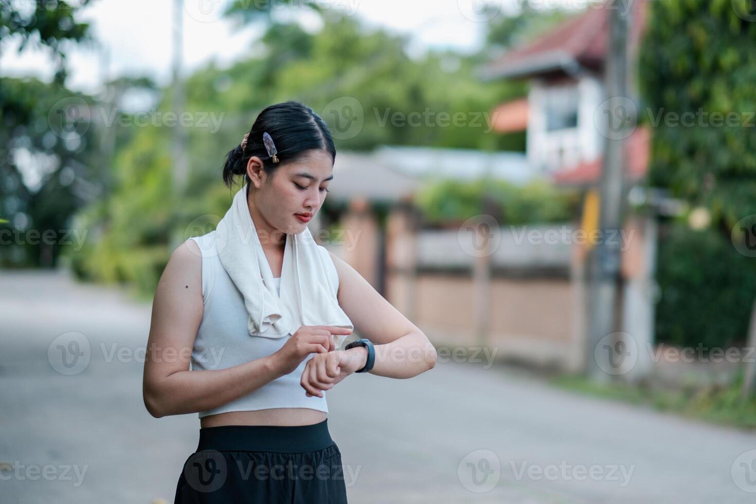 Young woman using a smartwatch while exercising outdoors in a suburban area, focusing on fitness and technology. photo
