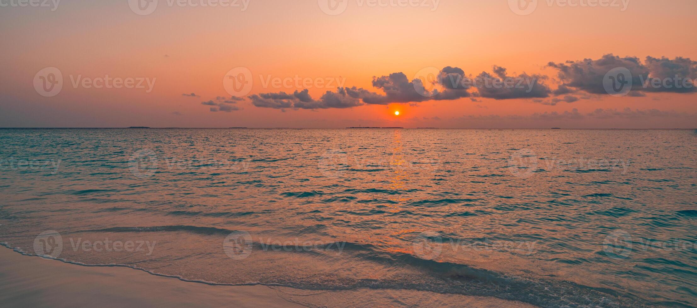 Sunset beach closeup featuring gentle sea waves, warm sand, and dramatic sky colors, tranquil tropical shore landscape inspiring dreamy travel, summer getaway, and nature escape photo