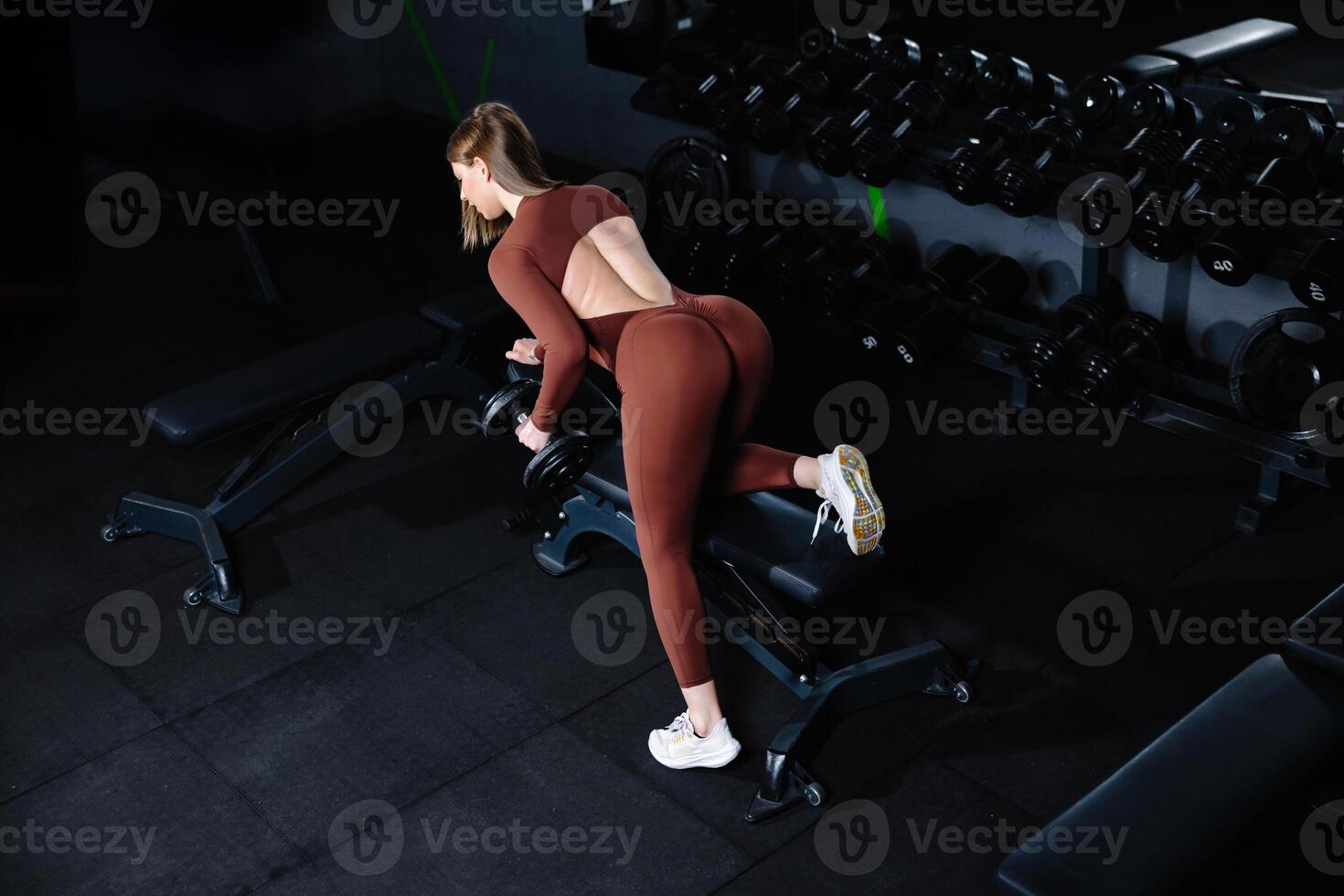 Female athlete lifting dumbbell during workout in gym. photo