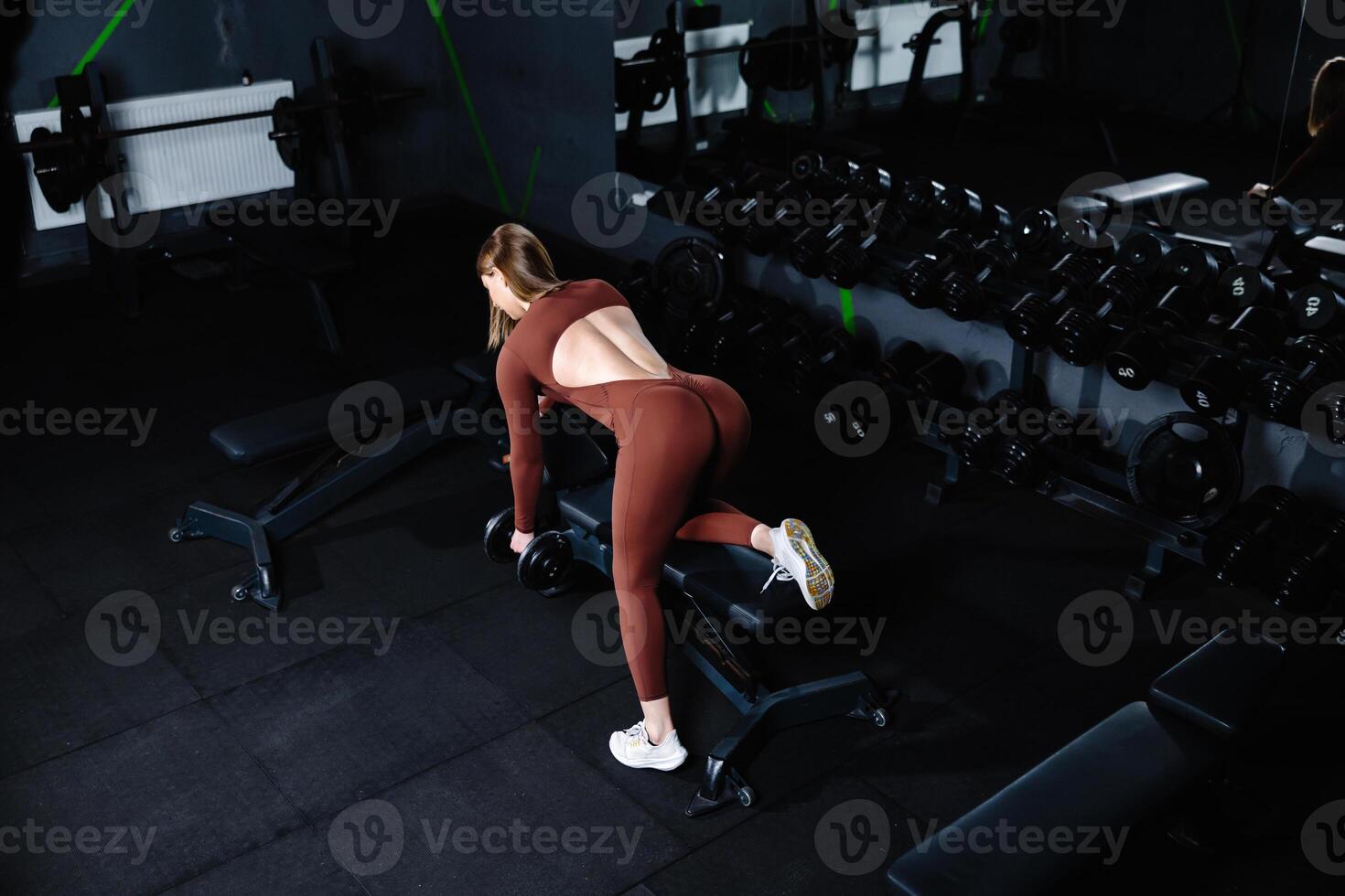 Female athlete lifting dumbbell during workout in gym photo