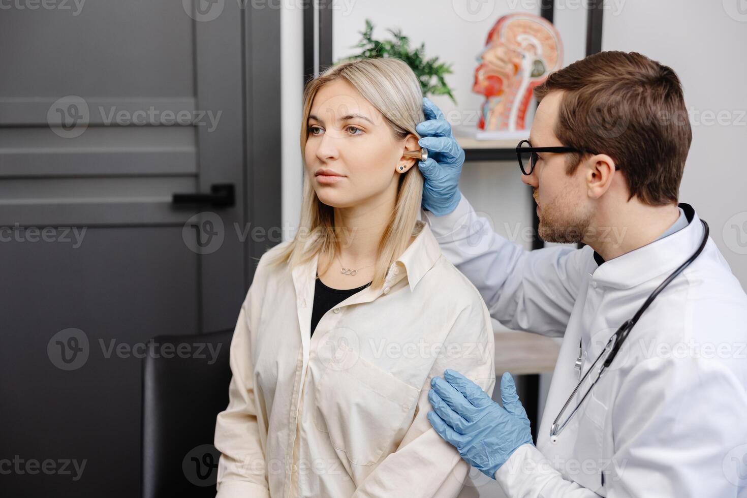 Otolaryngologist doctor checking young woman's ear using otoscope or auriscope at ENT clinic. photo
