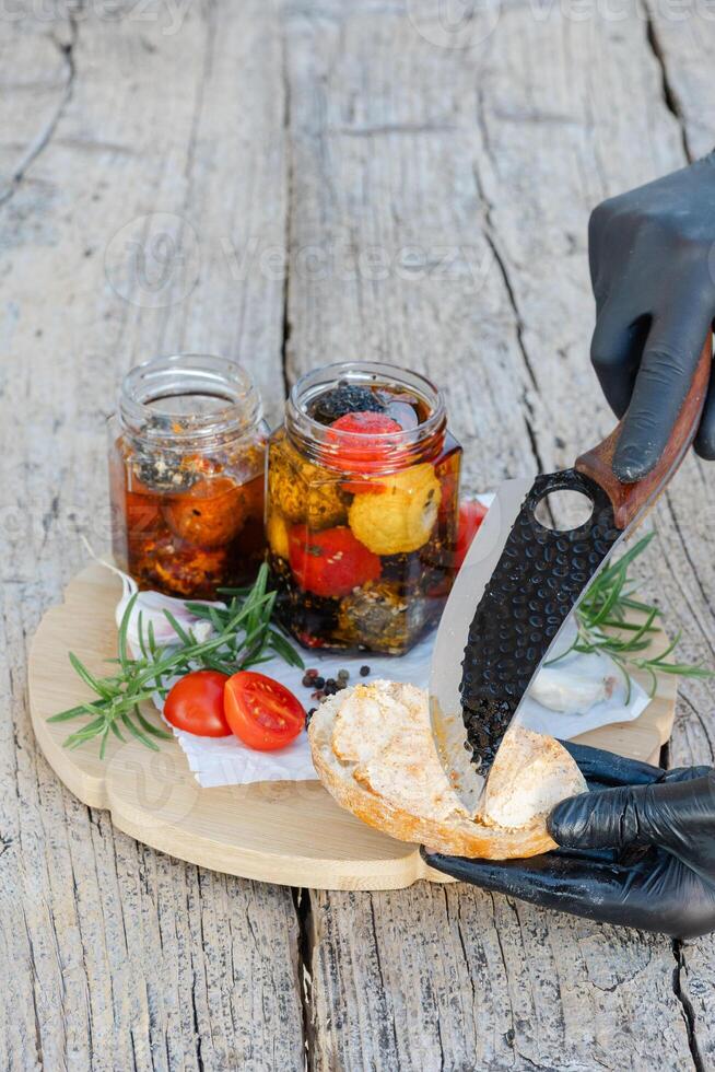 Chef spreading marinated cheese on toasted bread with cherry tomatoes and rosemary photo