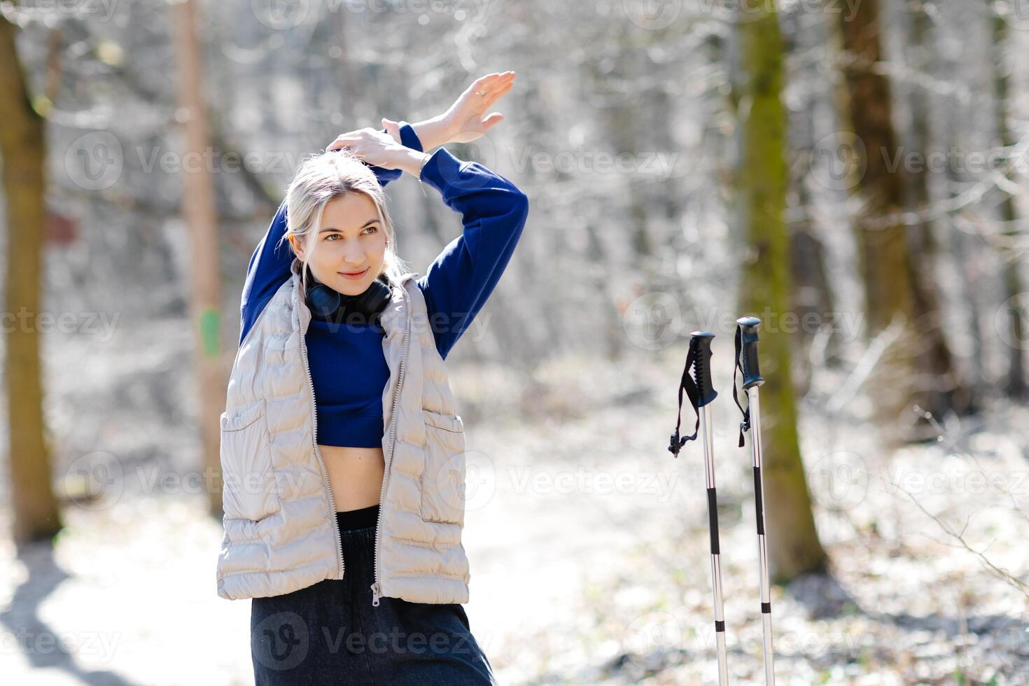 Young woman stretching before nordic walking in forest photo
