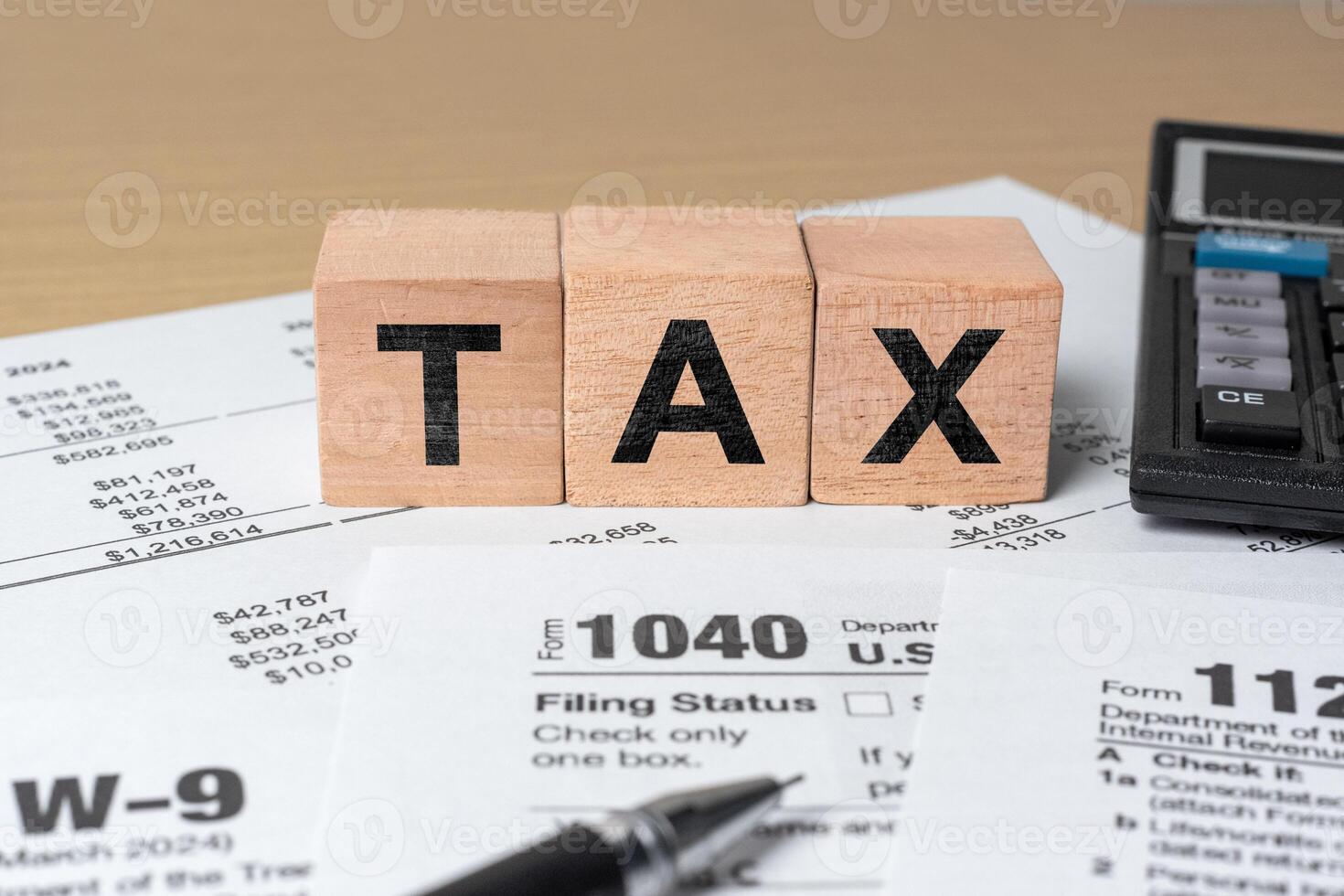 Filing taxes concept. Tax word on wooden cubes with calculator and pen placed on US 1040 income tax form for financial preparation photo