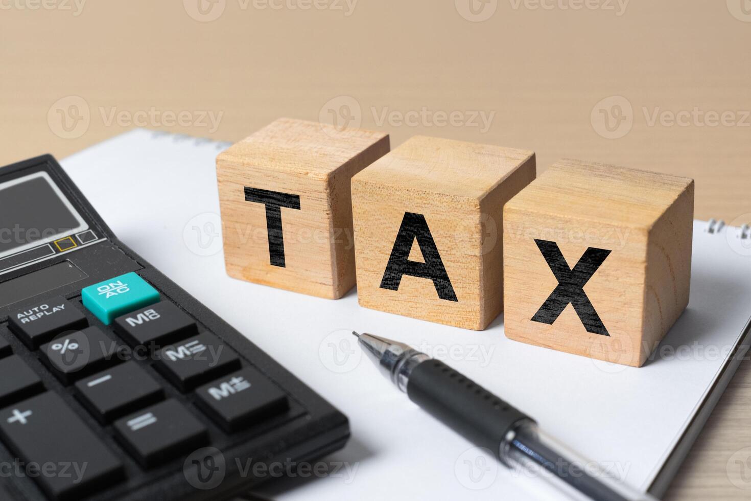 Wooden blocks spelling TAX with a calculator, pen, and notebook. Concept of tax calculation, financial planning, accounting, and business budget management photo