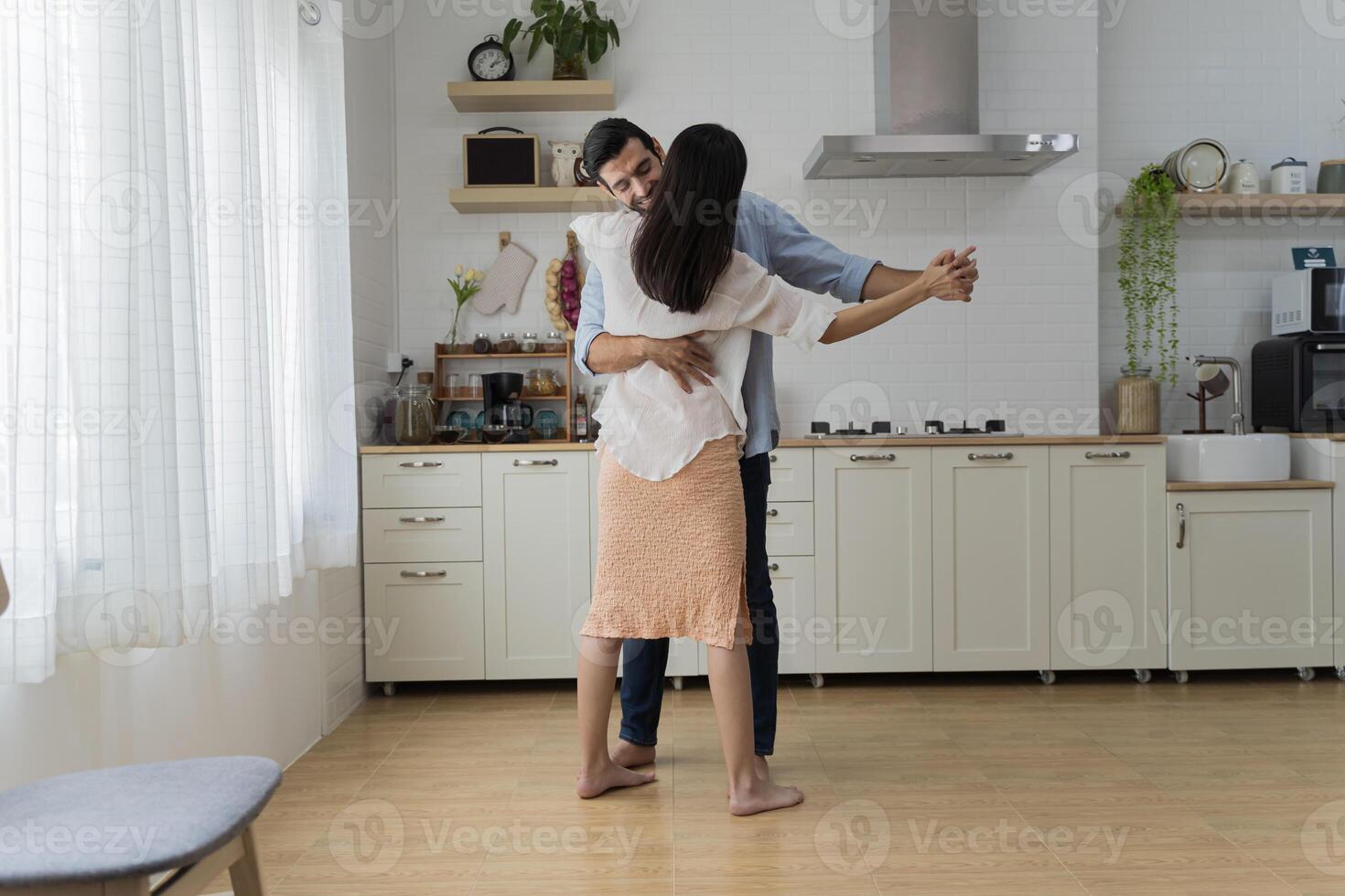 Romantic couple dancing together barefoot in kitchen, enjoying love and happy moment in cozy modern home photo