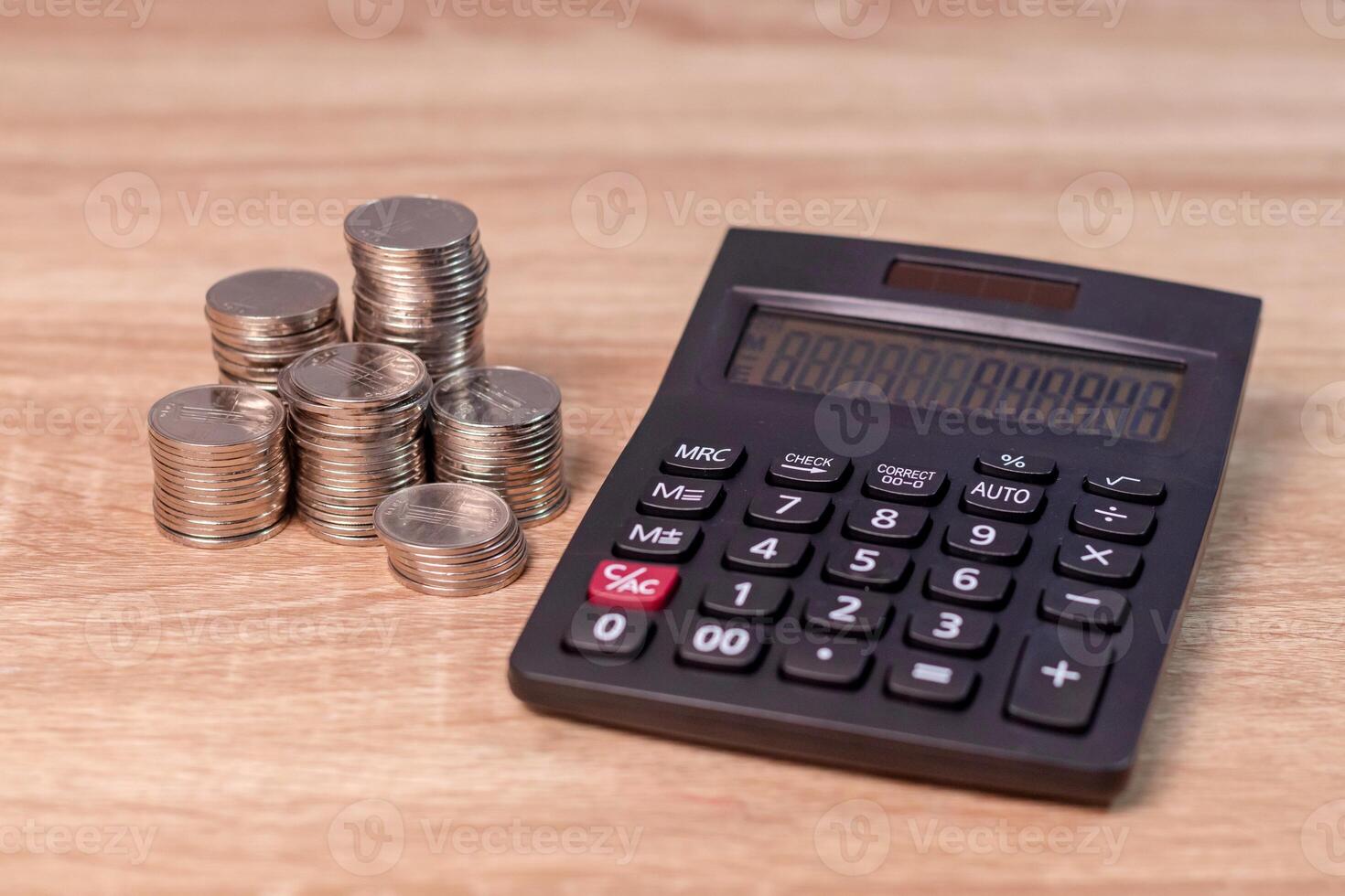 Finance, business, budget or investment concept. Stack of coins and calculator on wooden table. photo