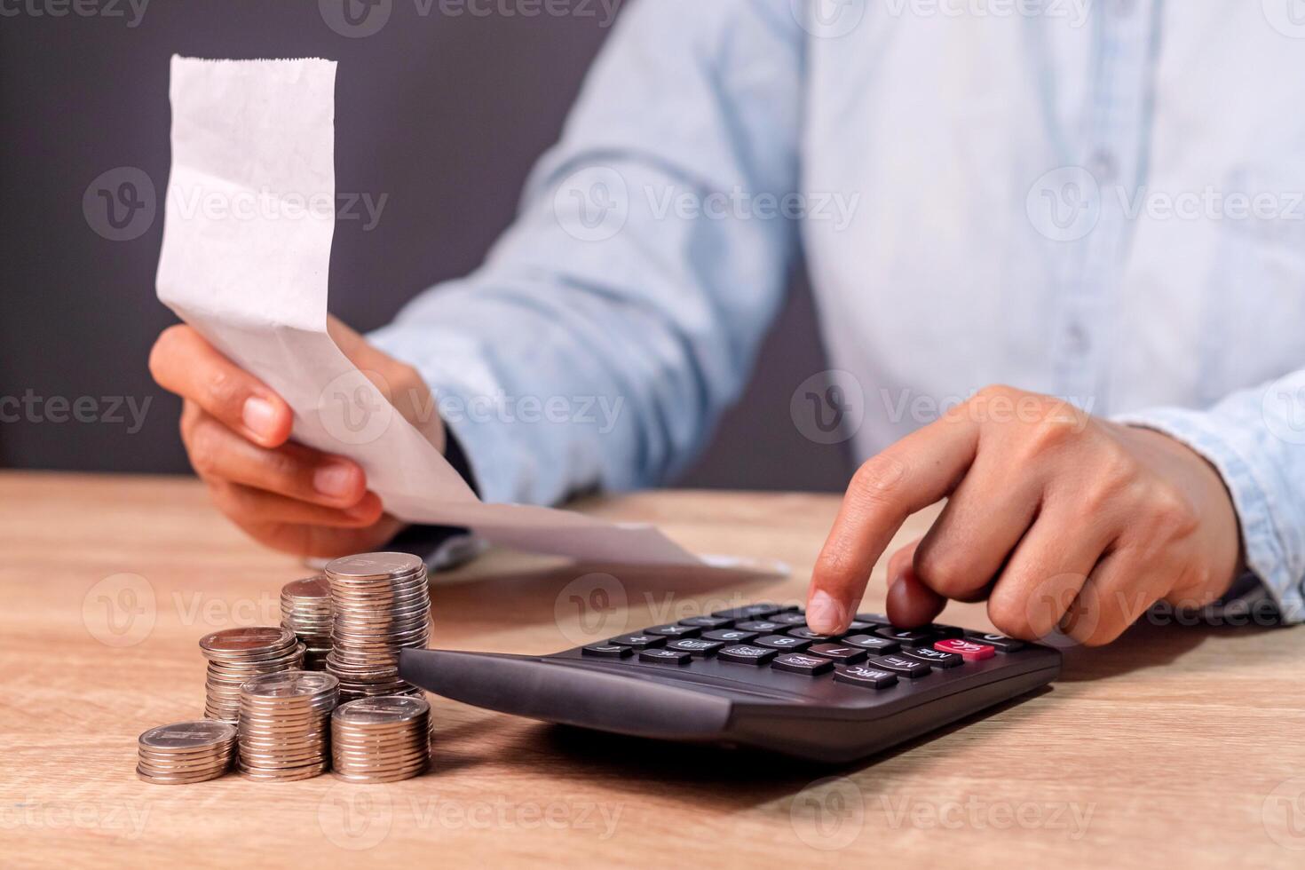 A woman holding a shopping receipt paper and calculating the expenses using calculator photo
