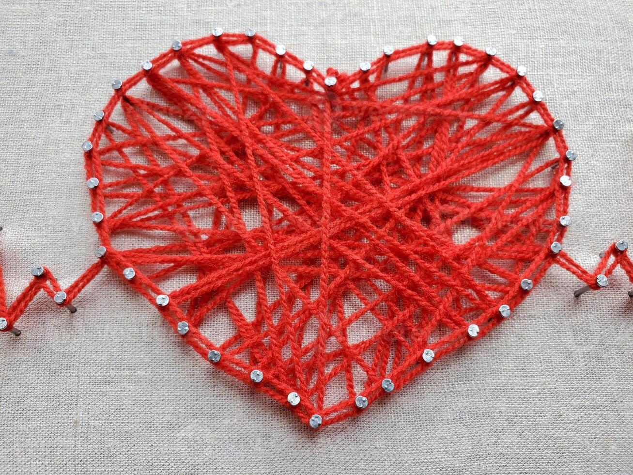 Creative heart design crafted from red yarn, adorned with shiny beads, showcasing intricate patterns and detailing that highlight artistic expression and craftsmanship in textile art photo