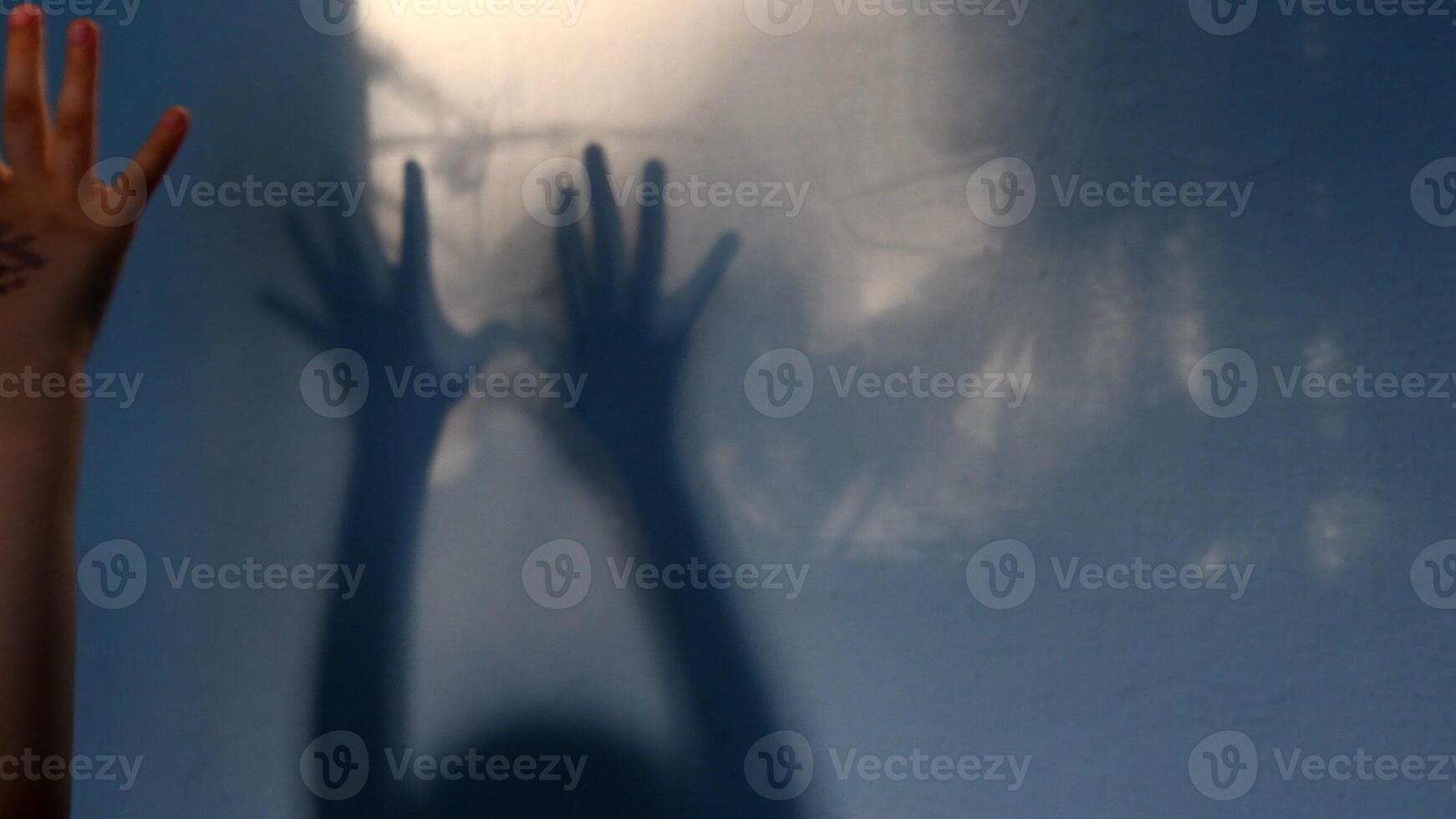 Blur shadows of child hands on wall. Game with light and shadow. Dark spooky silhouettes of hands for Halloween photo