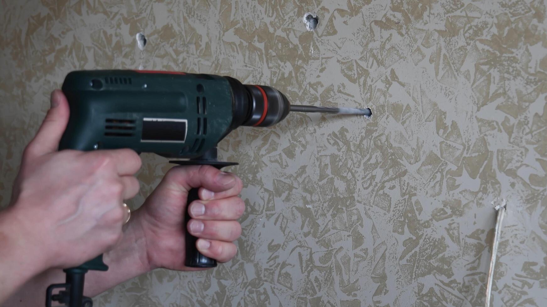 Male hands make hole using electric drill with twist drill bit photo