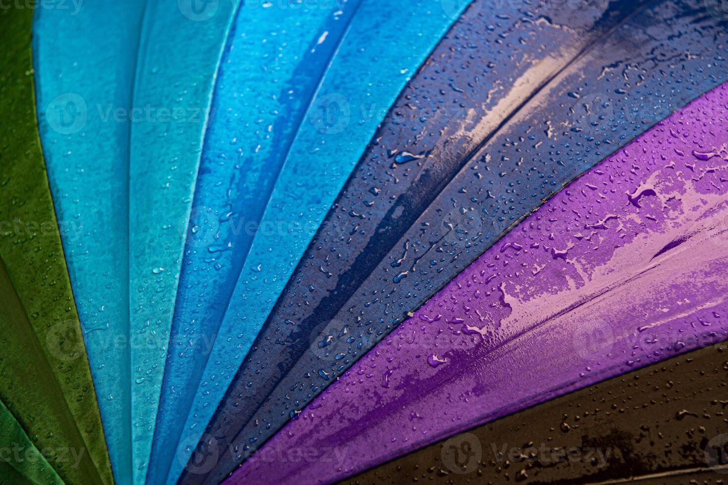 Raindrops on colorful shades umbrella closeup wet fabric texture photo
