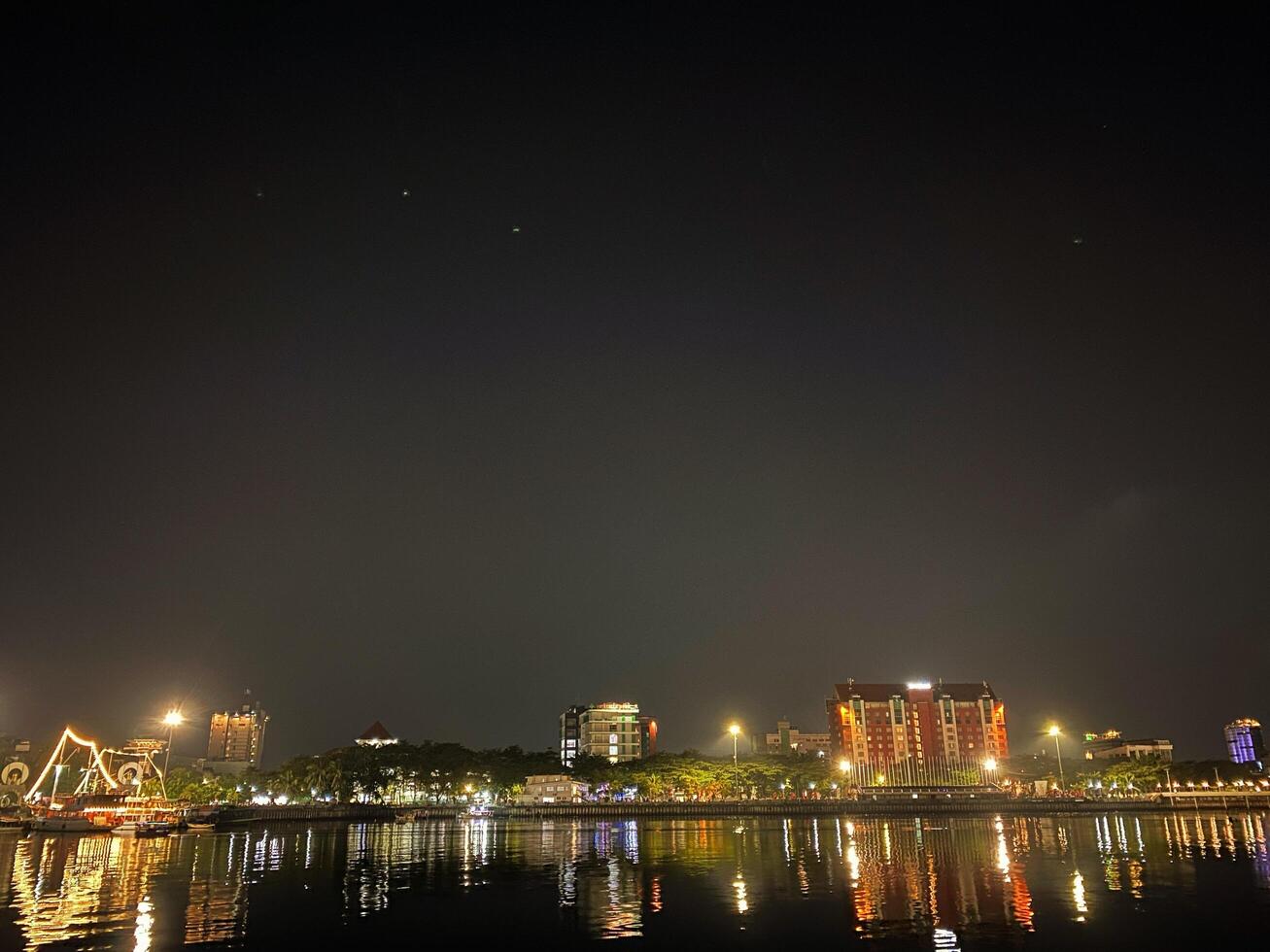 City lights reflect on the water creating a vibrant and captivating nighttime urban scene. photo