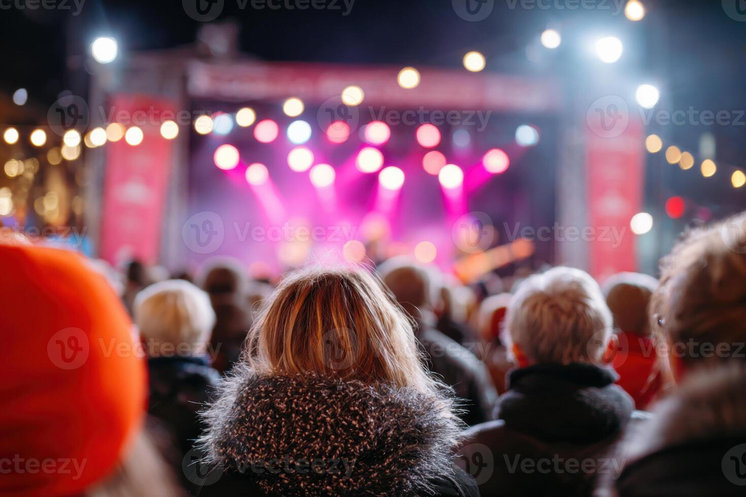 Crowd of concertgoers enjoying live music performance at night, illuminated stage with colorful lights, creating a vibrant atmosphere of excitement and energy photo