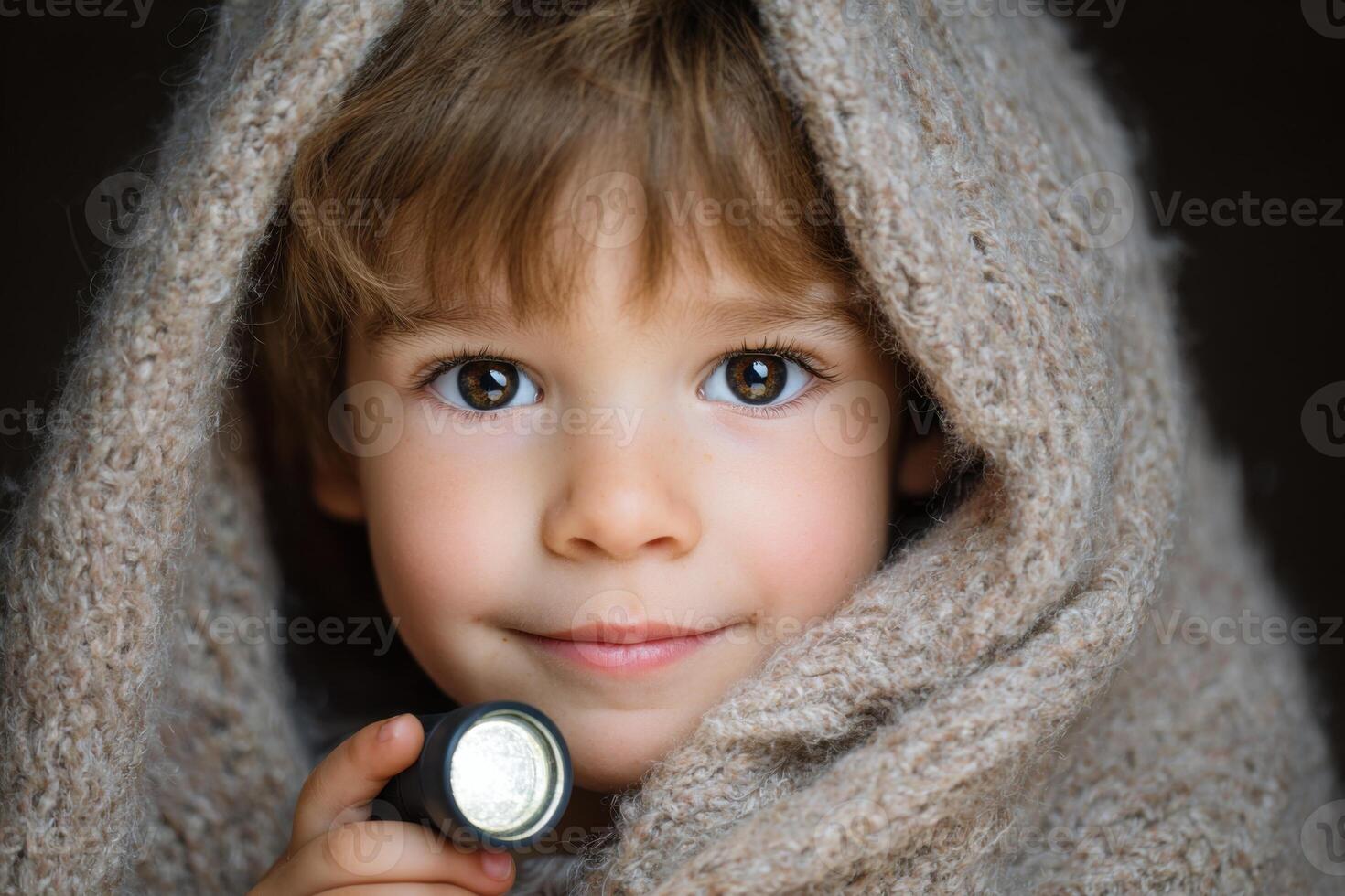 Young child wrapped in a cozy blanket, holding a flashlight, with a warm expression, creating a sense of comfort and curiosity in a soft, inviting atmosphere photo