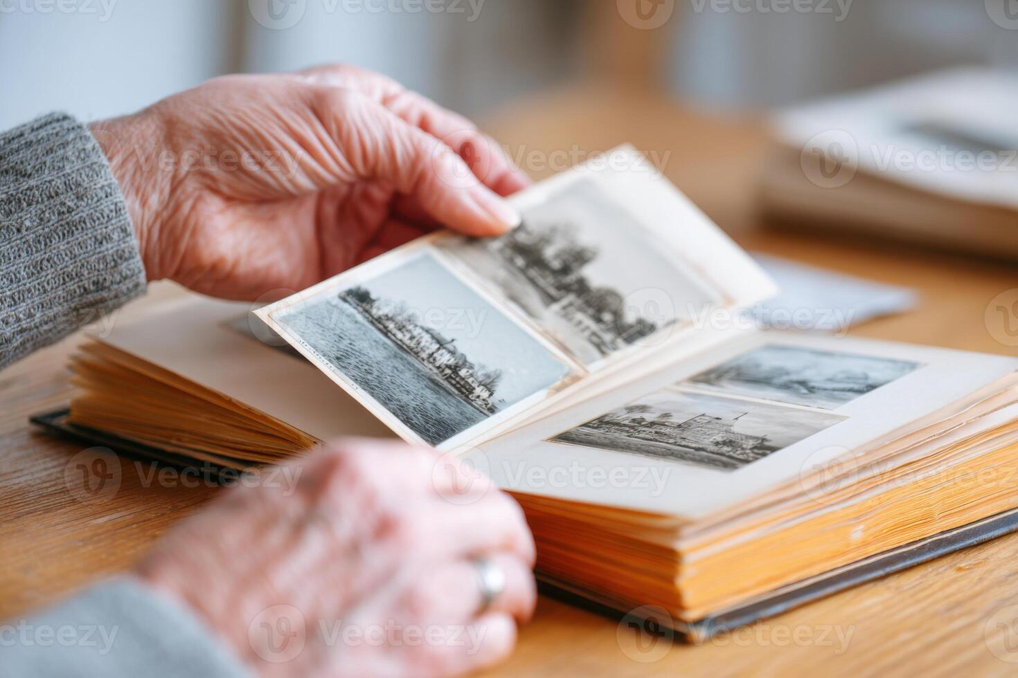 Hands of an elderly person gently flipping through a vintage photo album filled with black and white images, evoking nostalgia and memories of the past