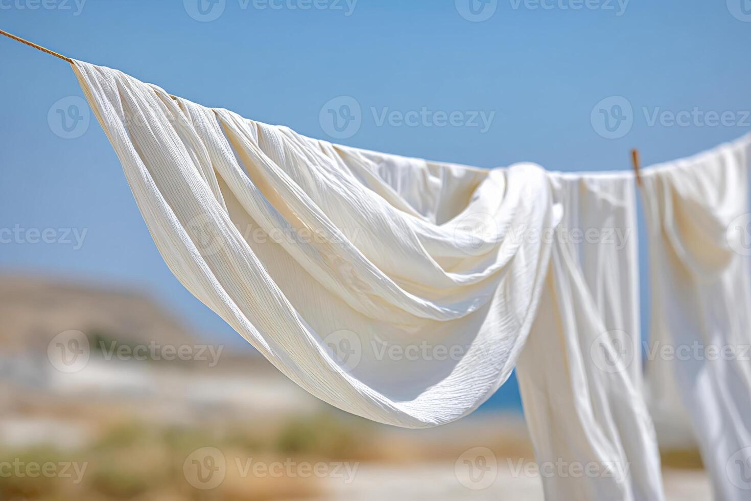 Flowing white fabric draped elegantly on a clothesline against a serene outdoor backdrop, capturing the essence of tranquility and natural beauty in a sunlit environment photo