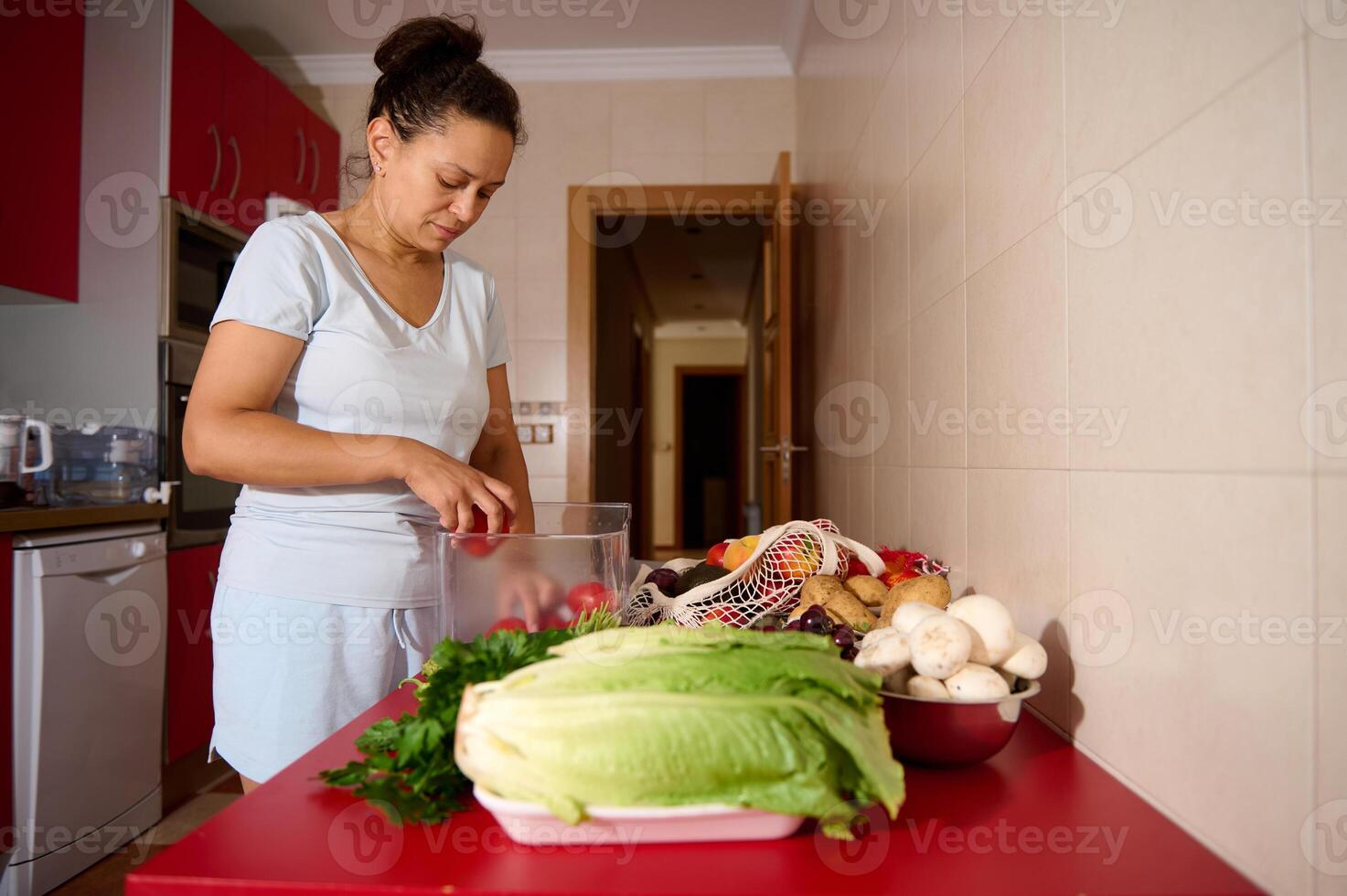 Woman Prepares Fresh Vegetables on Red Counter in Modern Kitchen photo