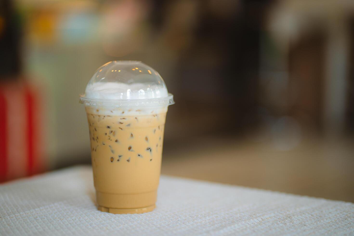 Glass of iced latte coffee on wooden table in coffee shop photo