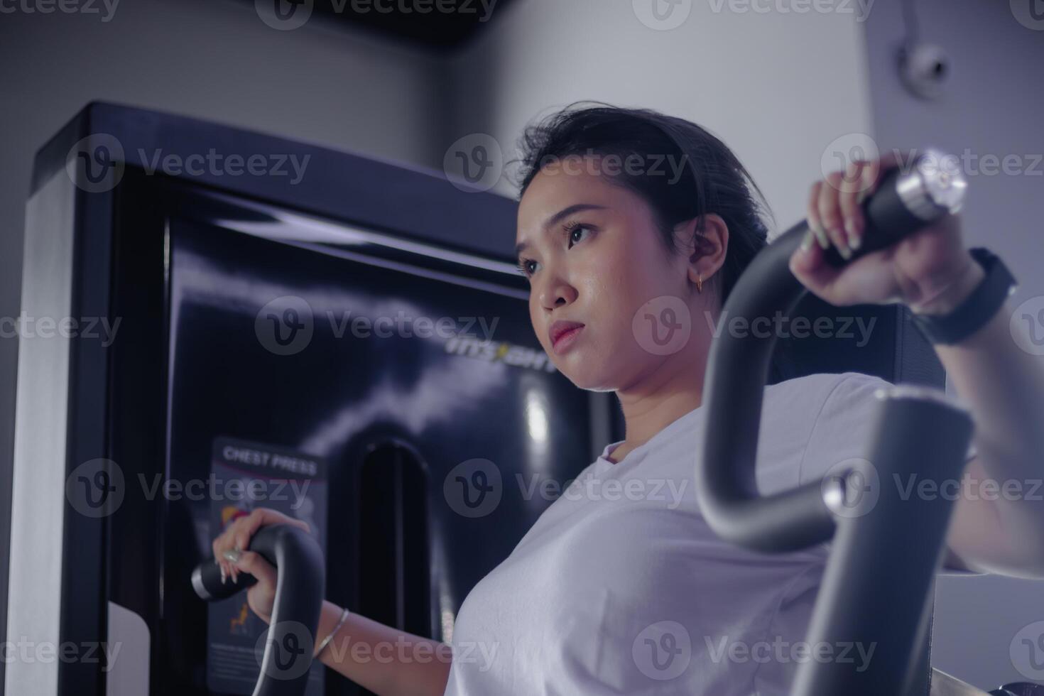 Determined woman exercising on chest press machine indoors gym photo