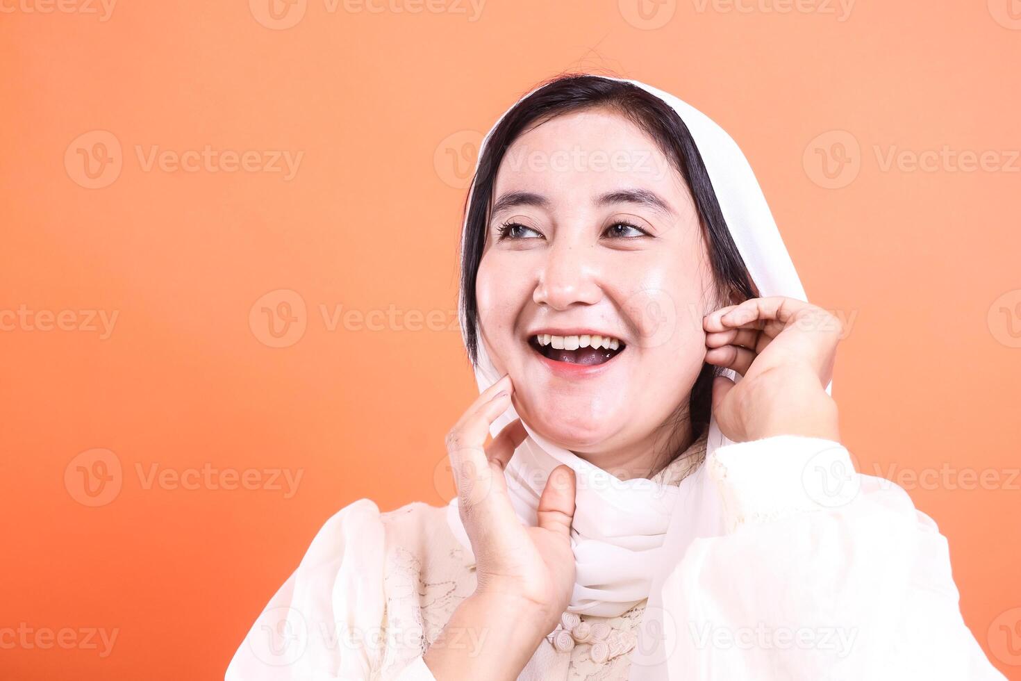Radiant Smile Portrait of a Muslim Woman in Hijab, expressing joy and contentment, with a soft, glowing complexion isolated on a orange background photo