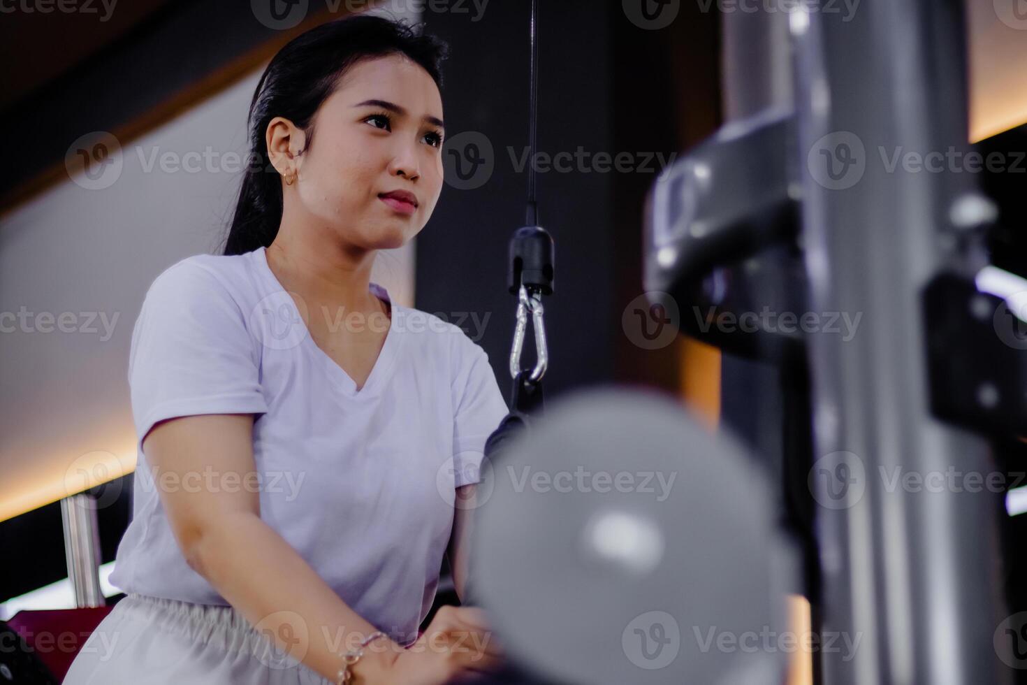 Focused young woman exercising with a lat pulldown machine indoo photo