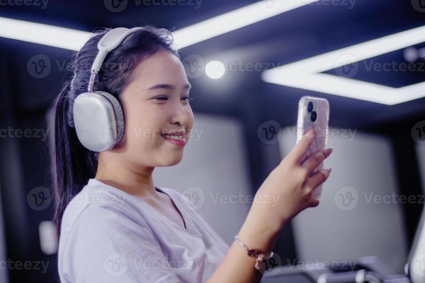 Smiling Asian Woman Enjoys Music with Headphones and Mobile Phon photo