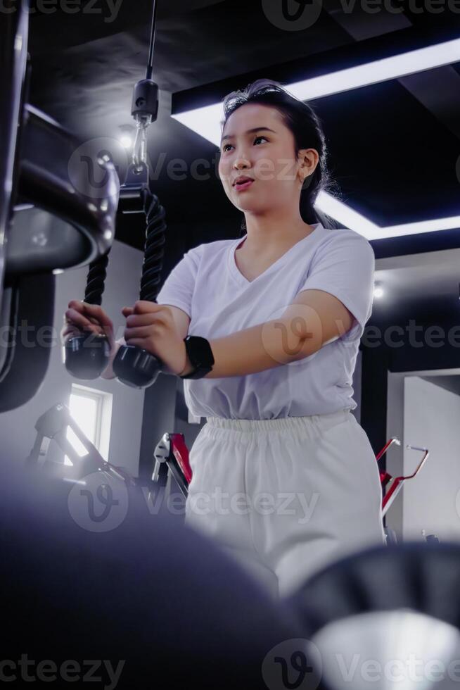 Focused young woman exercising on a machine at the modern fitnes photo