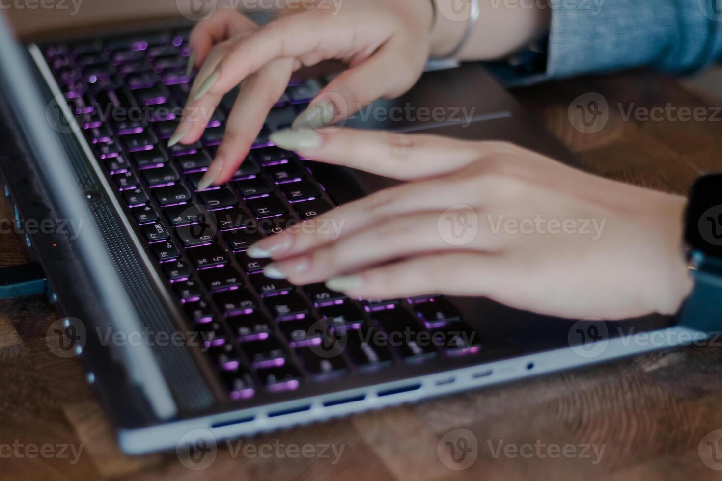Female hands typing on a modern laptop with illuminated keyboard photo