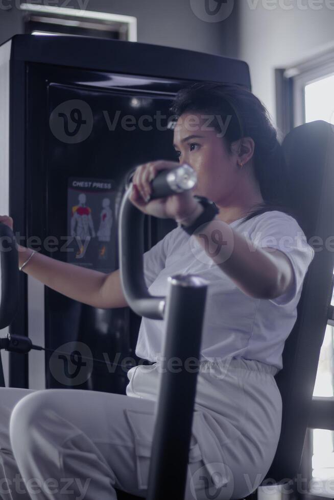Focused woman enhances chest power utilizing pressing machine in photo