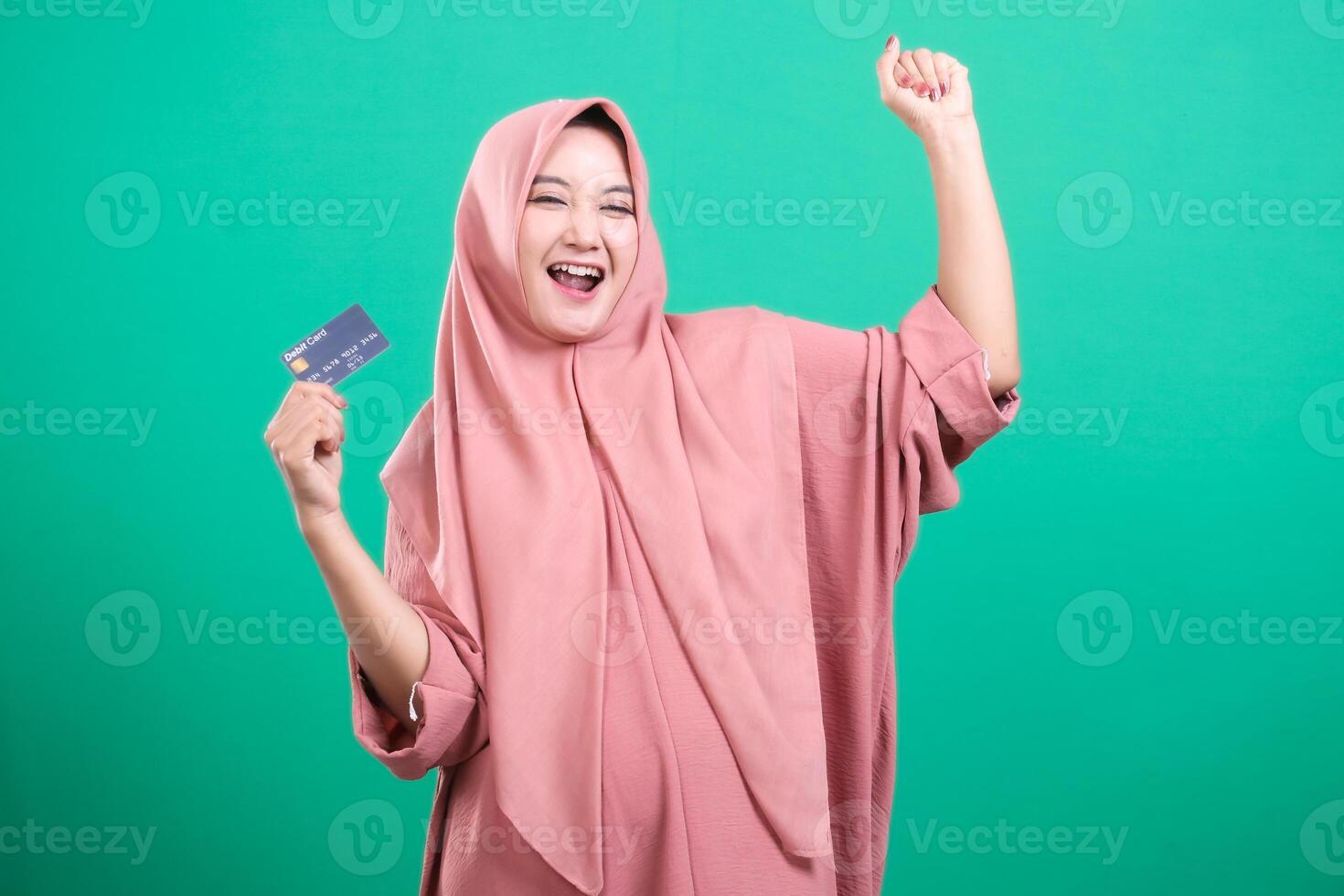 Excited muslim woman rejoices with credit card, arm raised in a photo