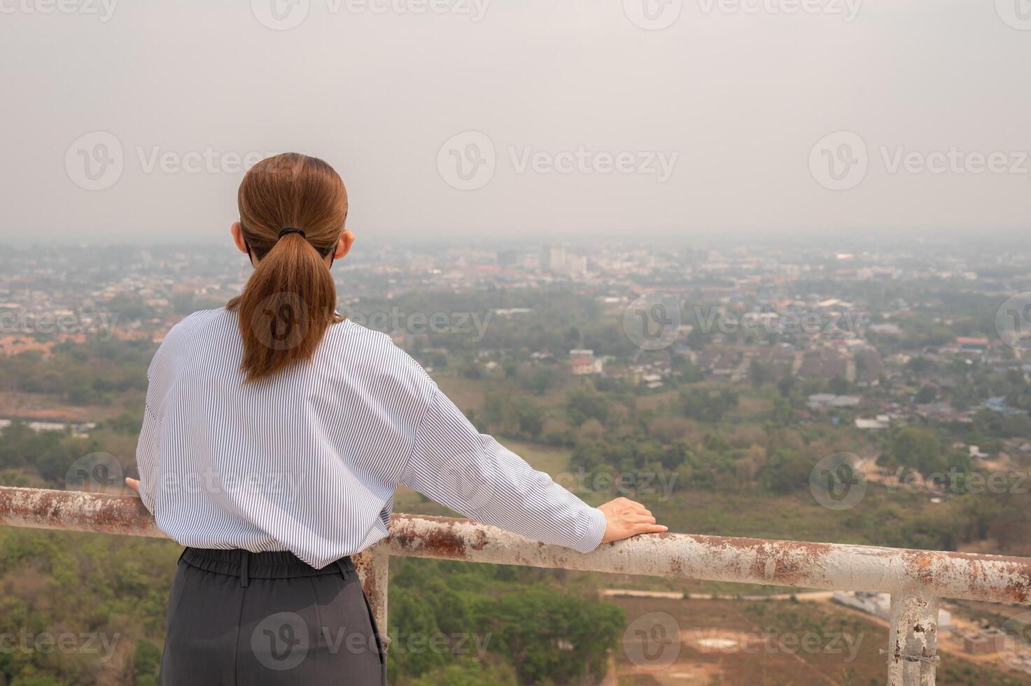 Rear view of Asian businesswoman looking to her hometown cover by bad air pollution. photo