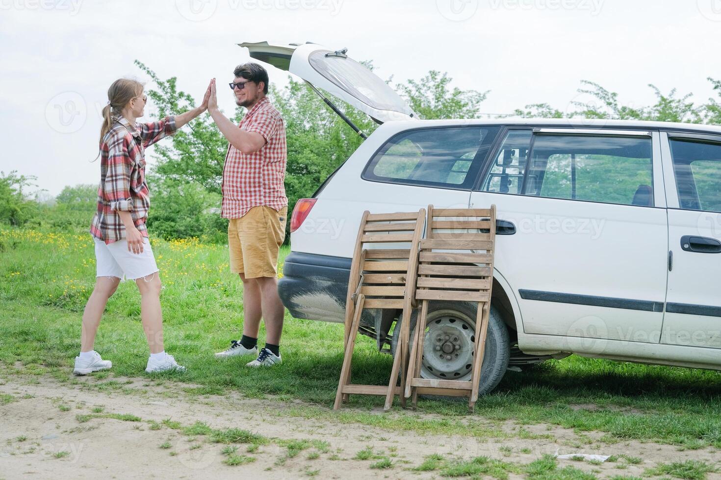 Couple on picnic, gathering table and chairs into the car photo