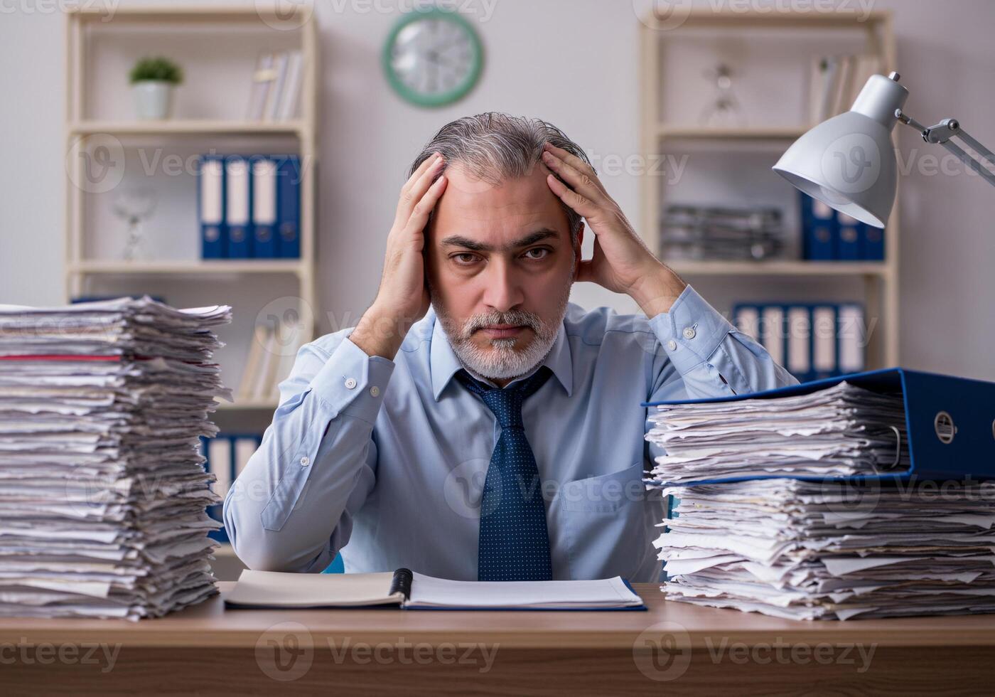 Stressed man worries about economy with holding hand and document, between stack of document 1 photo