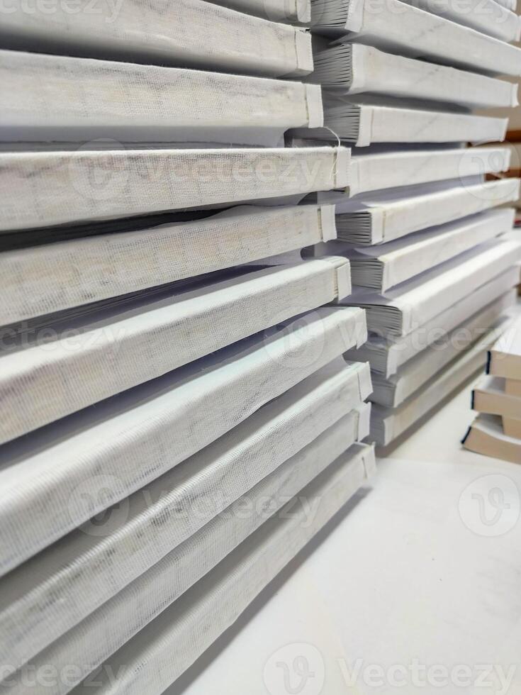 Close-up, stack of glued book blocks prepared for binding in a printing house, vertical photo