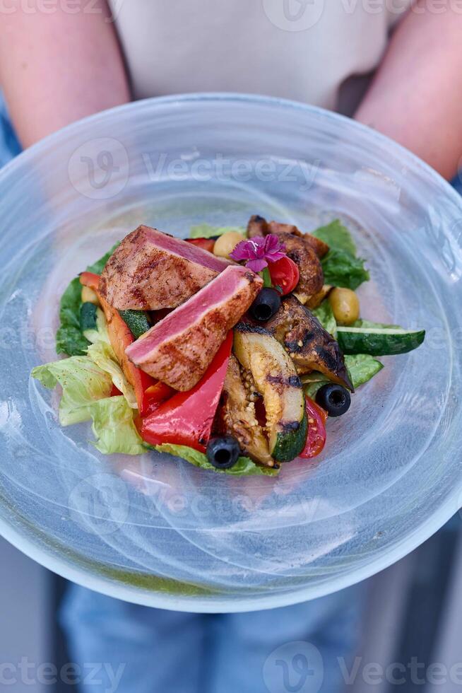 Salad with tuna, olives and vegetables in a glass bowl photo